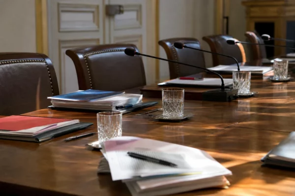 Salle de réunion institutionnelle à l’Élysée avec table, micros et dossiers, évoquant une rencontre politique officielle.