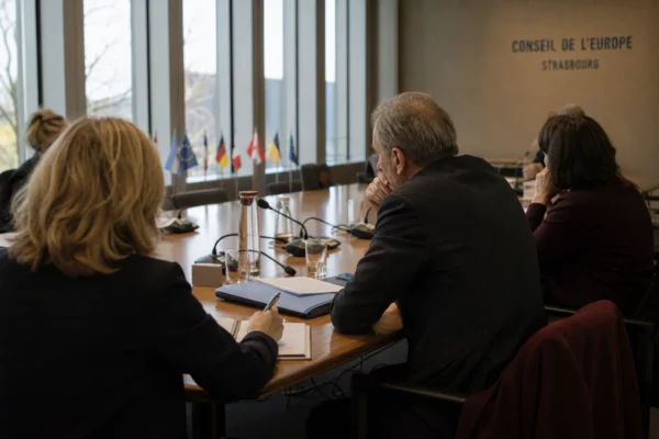 Réunion européenne à Strasbourg, avec des députés anonymes autour d’une table couverte de dossiers et de micros