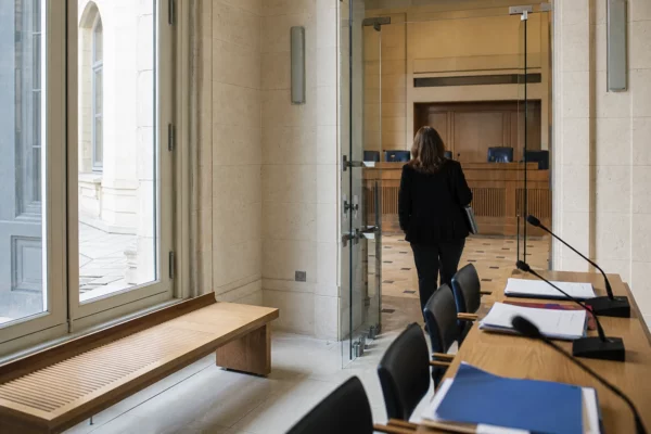 Couloir lumineux d’un bâtiment institutionnel français ouvrant sur une salle d’audition constitutionnelle vide