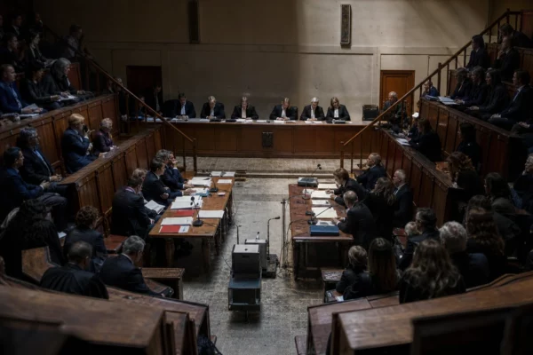 Salle d’audience vide de la cour d’appel de Paris, avec bancs de bois usés, tables de la défense et du parquet, micros et dossiers.