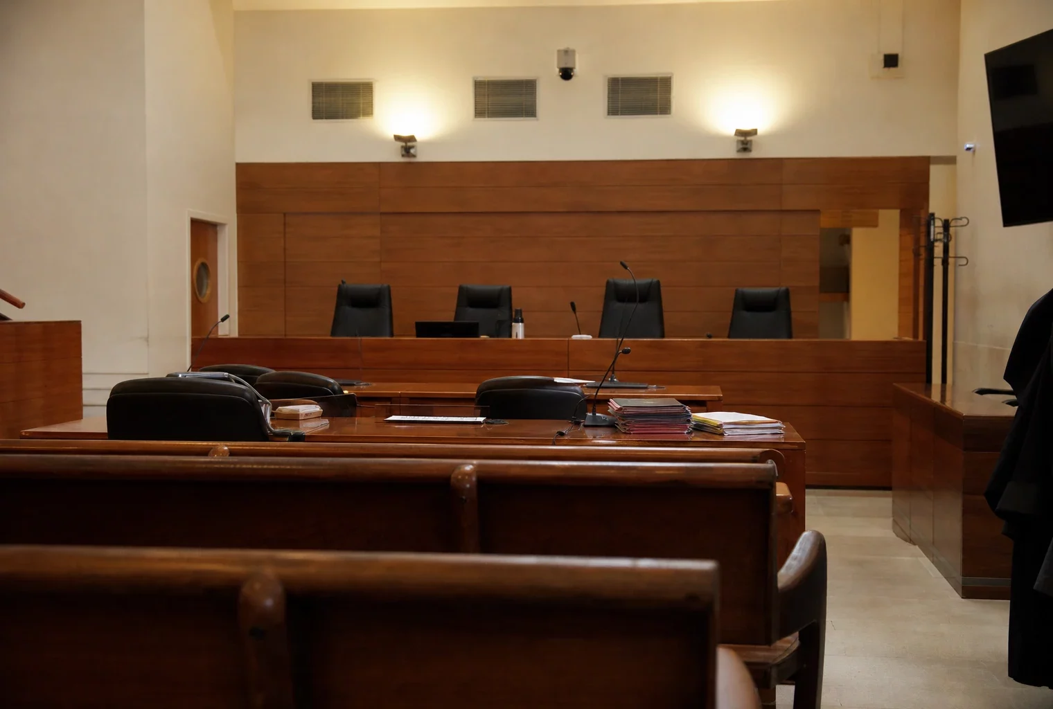 Salle d’audience vide dans un tribunal, avec bancs et tables, pour illustrer la traduction concrète des moyens annoncés.