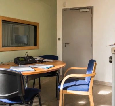 Salle d’audition pédiatrique avec table, chaises et matériel d’enregistrement dans un hôpital français.