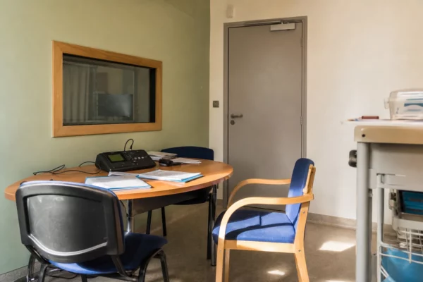 Salle d’audition pédiatrique avec table, chaises et matériel d’enregistrement dans un hôpital français.