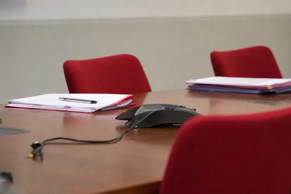 Salle de réunion vide d’un parti, avec table et chaises, où se prépare une décision interne sur une suspension.