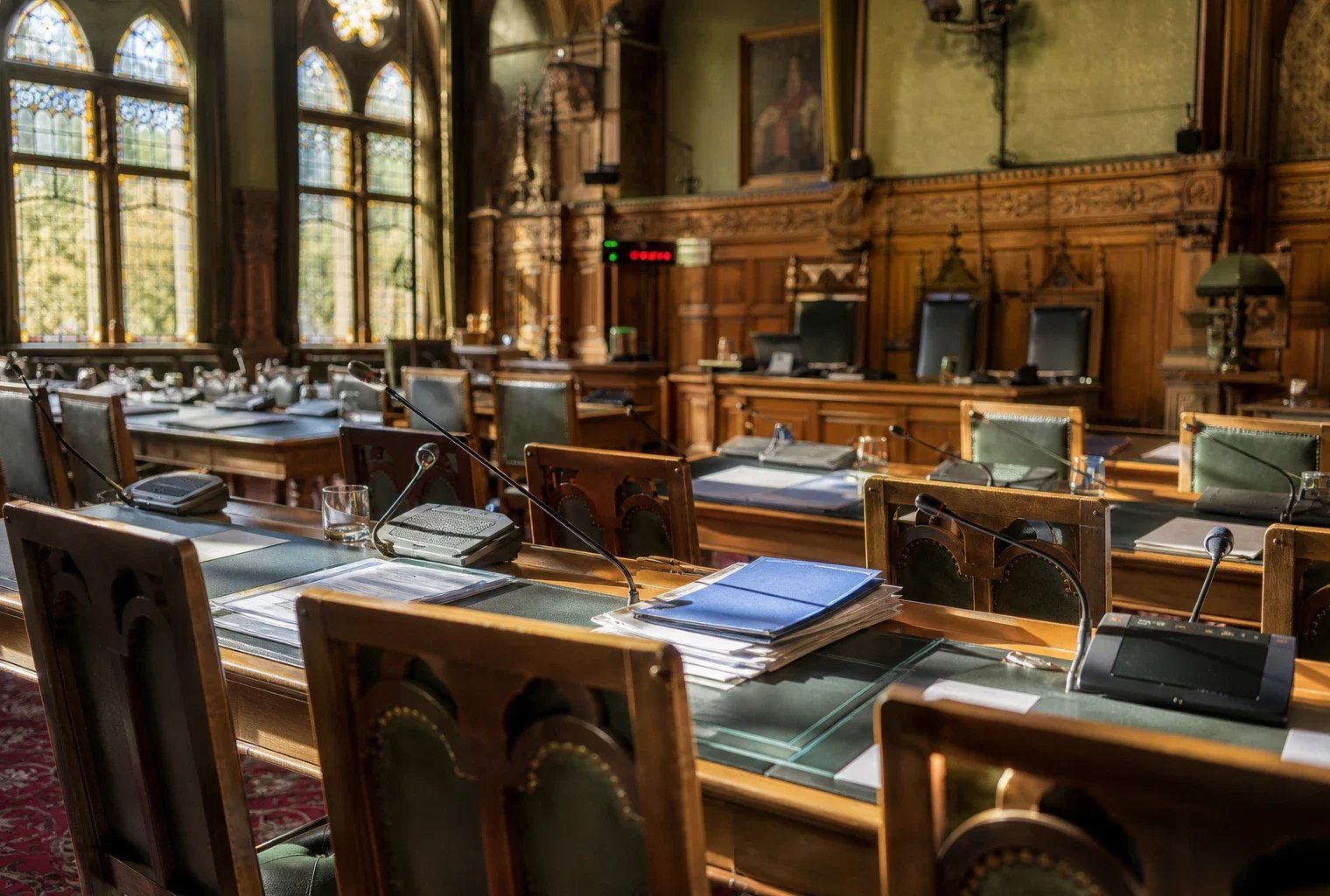 Salle de commission du Sénat au Palais du Luxembourg, tables alignées, micros et dossiers, sous la lumière du matin.