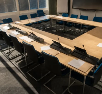 Salle de commission du Sénat à Paris, vue plongeante sur une table de réunion, pupitres, micros et dossiers laissés en place.