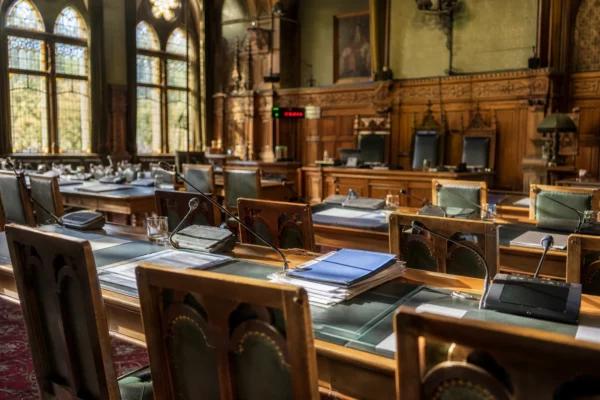 Salle de commission du Sénat au Palais du Luxembourg, tables alignées, micros et dossiers, sous la lumière du matin.