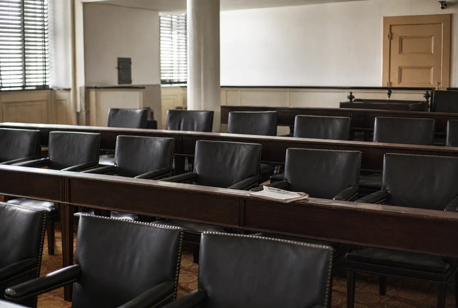 Salle du conseil municipal vide dans une mairie du Doubs, tables en bois, chaises alignées et lumière douce neutre.