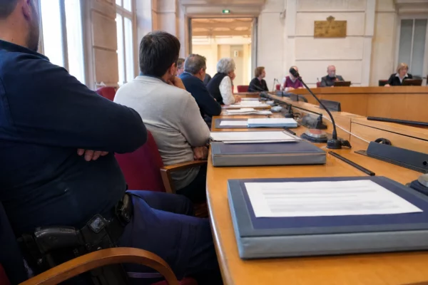 Salle municipale française avec chaise vide, micros et dossiers lors d’une scène de conseil local