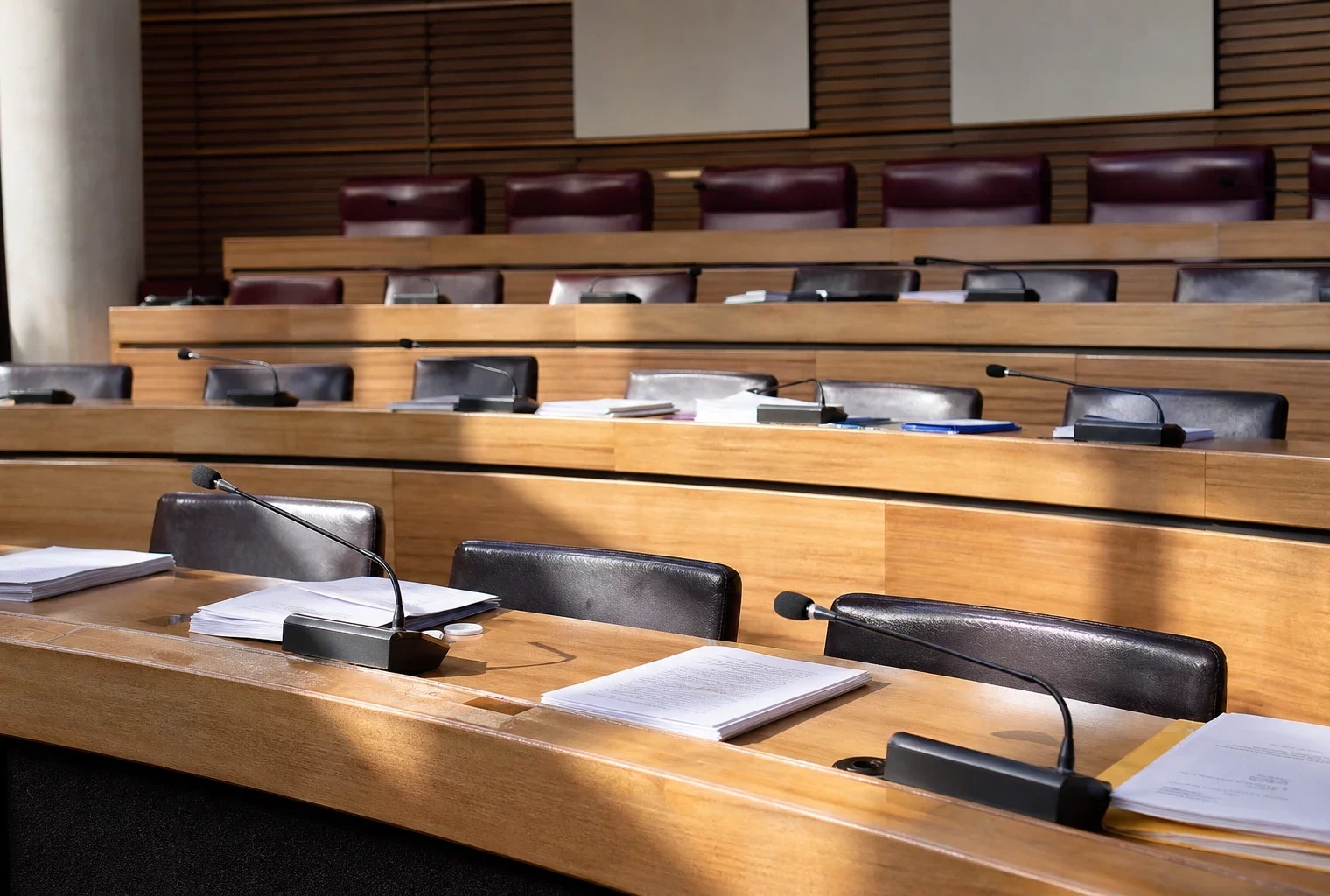 Salle de conseil régionale vide avec pupitres et micros, où se prépare la décision politique locale.