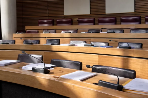 Salle de conseil régionale vide avec pupitres et micros, où se prépare la décision politique locale.