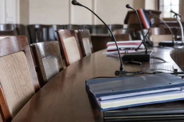 Salle du conseil municipal d’une petite commune, avec pupitres, micros et chaises vides en mairie.