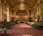 Salle des fêtes de l’Élysée en préparation, chaises alignées, pupitre discret et lumière d’hiver sur le décor officiel.