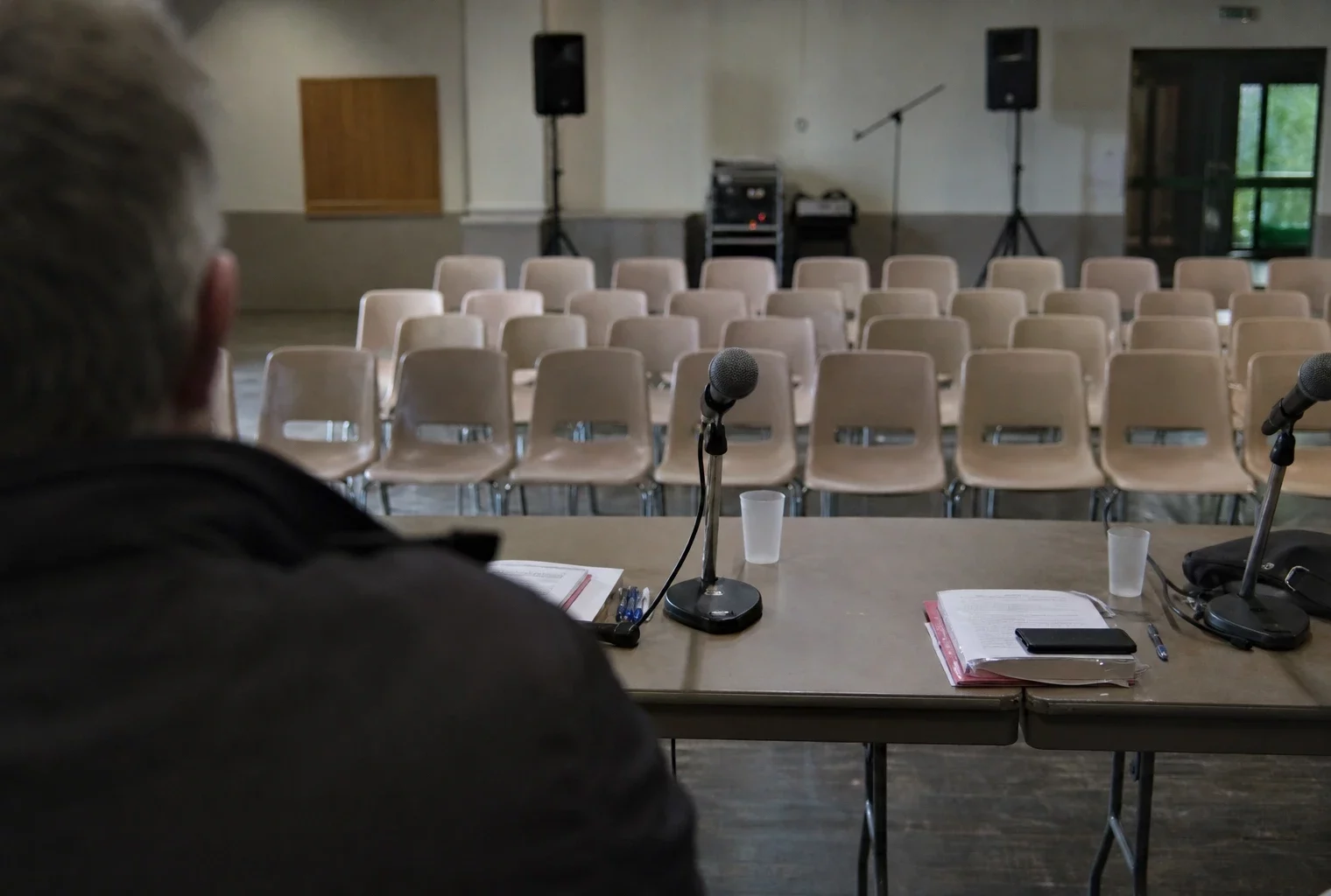 Salle de meeting avec micros et chaises alignées, lors d’un rassemblement politique local à Levens.