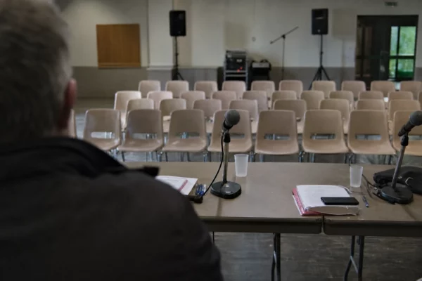 Salle de meeting avec micros et chaises alignées, lors d’un rassemblement politique local à Levens.