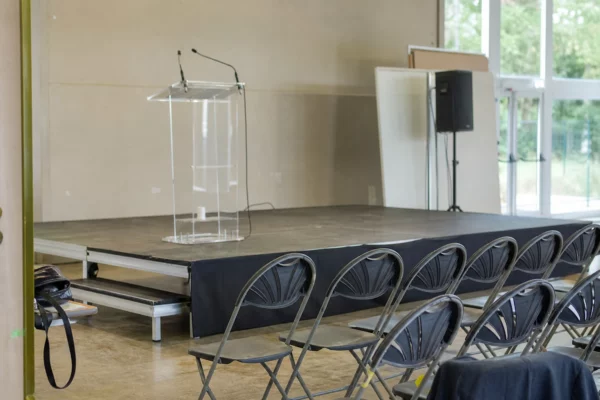 Salle de réunion politique avec estrade, pupitre et rangées de chaises, lors d’une rentrée militante à L’Isle-sur-la-Sorgue