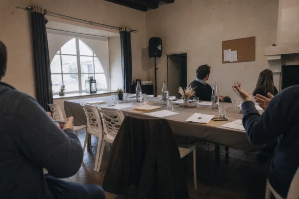 Salle de réunion de parti en France, tables serrées, dossiers et mains en discussion sous une lumière grise de pluie.