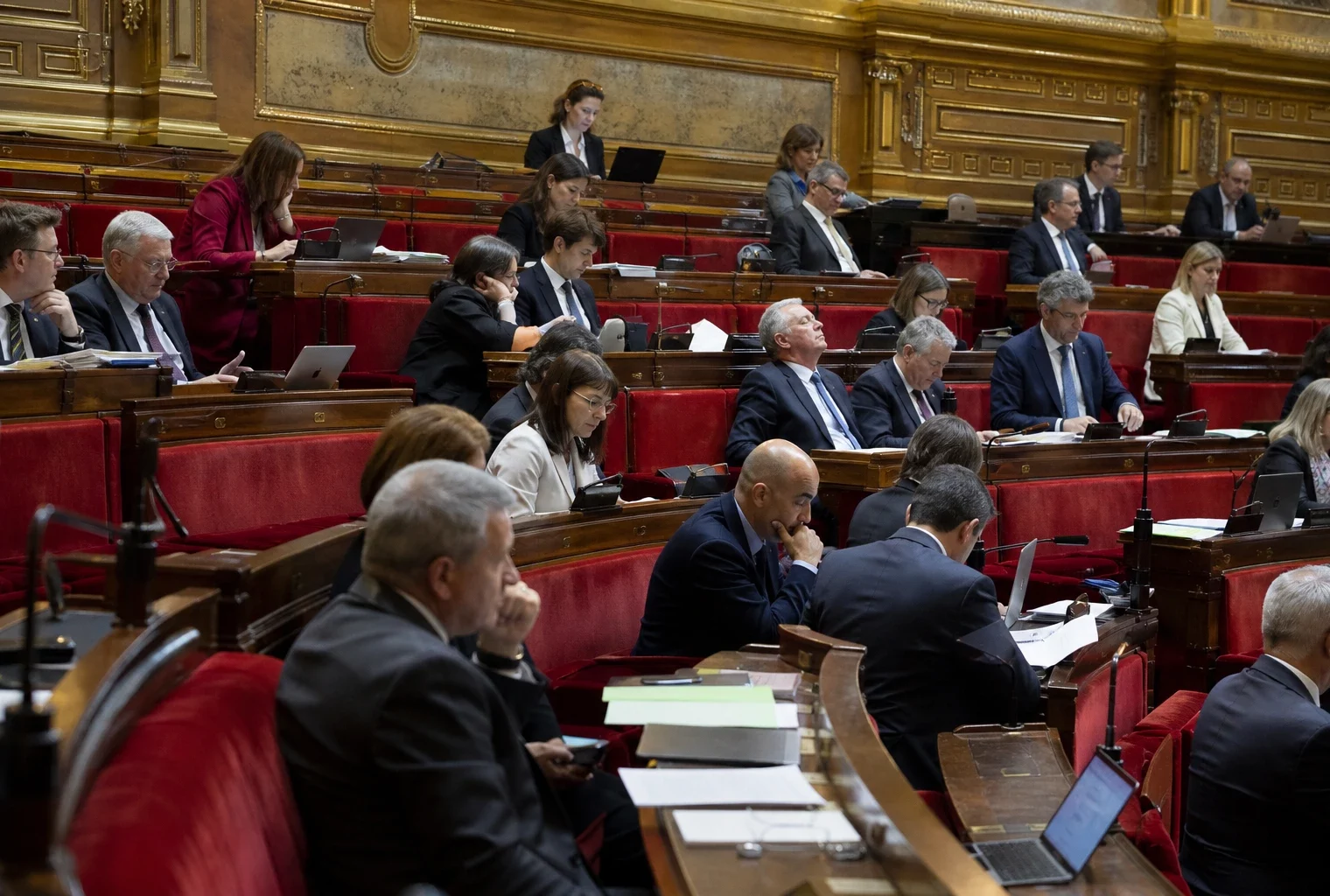 L’hémicycle du Sénat avec ses rangées de sièges et de pupitres, vide lors d’un moment de séance.