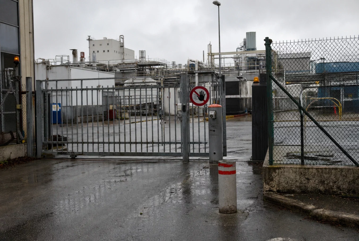 Un site industriel sécurisé avec clôture, portail d’accès et bâtiments techniques en arrière-plan.