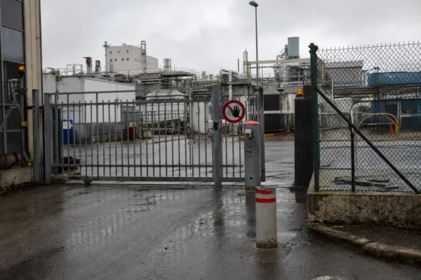 Un site industriel sécurisé avec clôture, portail d’accès et bâtiments techniques en arrière-plan.
