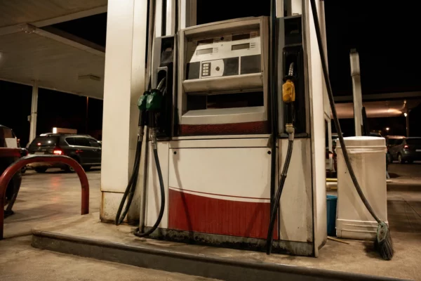 Pompes d’une station-service en bord de route, avec des voitures en arrière-plan.