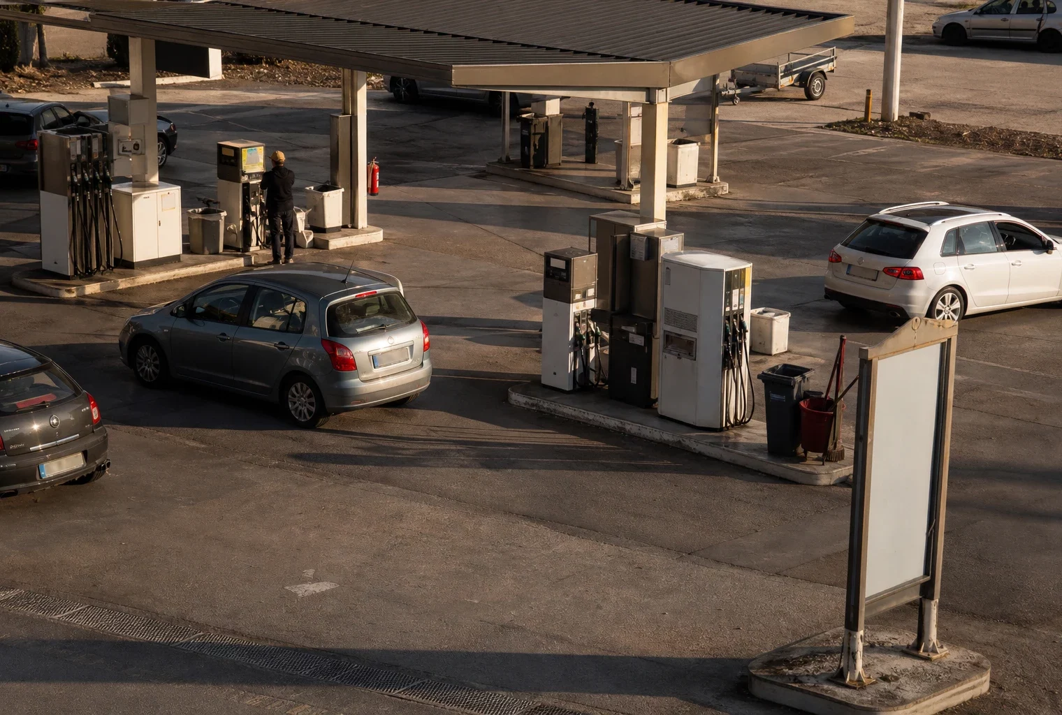 Une station-service de bord de route avec ses pompes à carburant et des voitures en attente.
