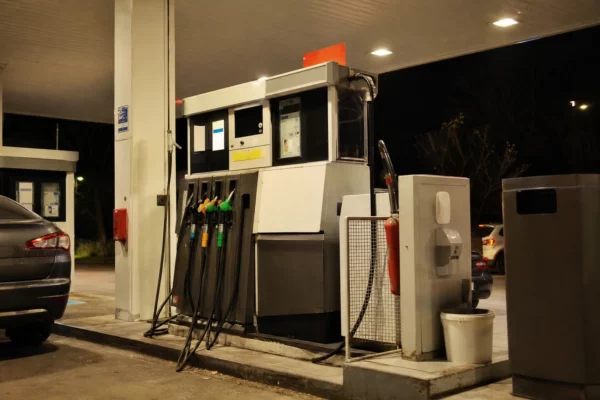 Une pompe de station-service en France, avec l’affichage des prix et des voitures en attente.