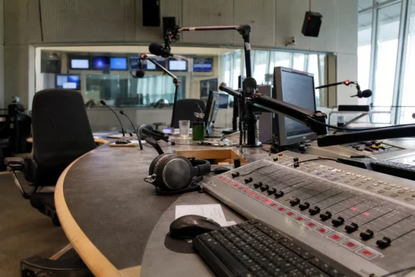Studio de radio publique avec micros, console et casques, évoquant la diffusion et les perturbations d’antenne.
