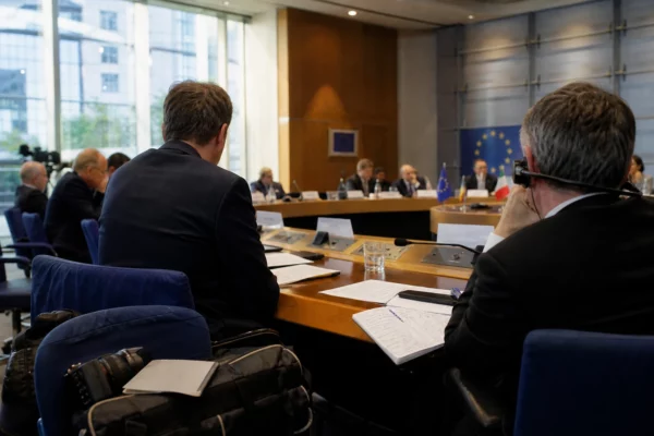 Table de négociation au Parlement européen à Strasbourg, avec dossiers, écouteurs et silhouettes anonymes
