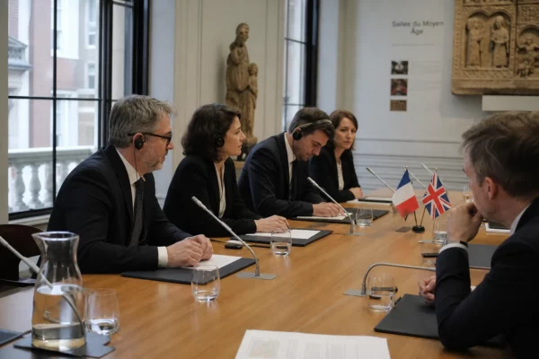 Table de négociation franco-britannique avec micros, dossiers et écouteurs dans un musée londonien