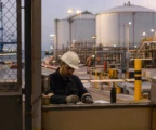 Gros plan sur des mains de sécurité près de réservoirs pétroliers et de tuyauteries dans un port industriel au crépuscule.