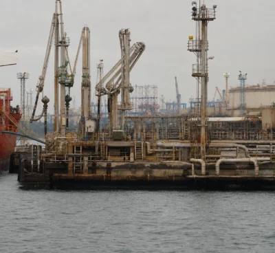 Terminal pétrolier de Yanbu avec navire-citerne, bras de chargement et quais industriels sous ciel couvert.