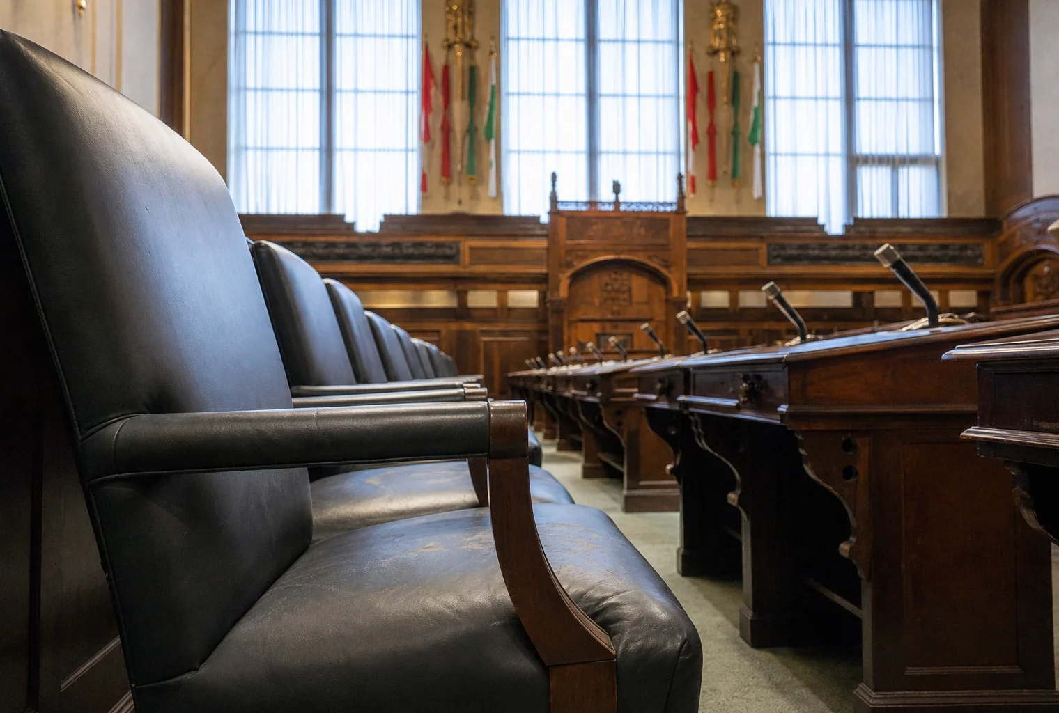 Salle d’audience vide du tribunal correctionnel, bancs en cuir, tables de défense et tribune sous lumière froide.