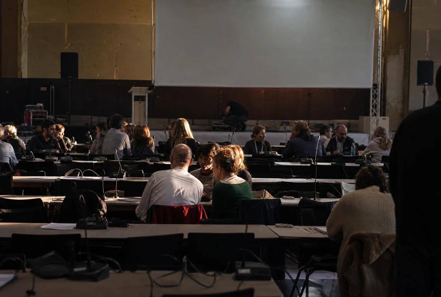 Salle de conférence vide avec chaises, micros et estrade pour les universités d’été de La France insoumise à Marseille.