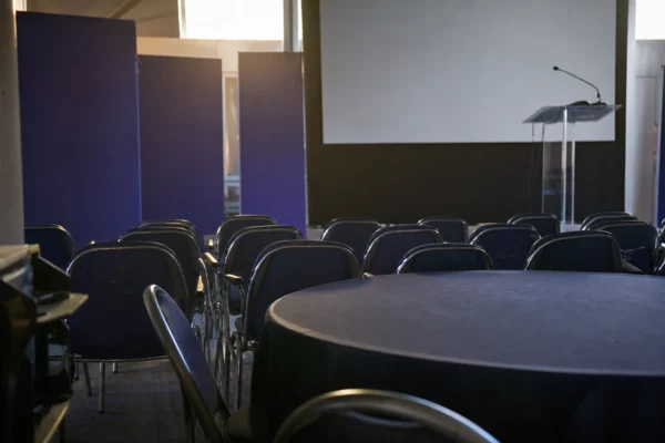 Salle de conférence politique avec rangs de chaises et table ronde vide lors d’une université d’été à Port-Marly