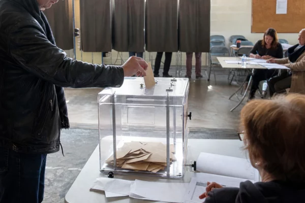 Une urne de vote dans une salle municipale, avec isoloirs et table de dépouillement pour des grands électeurs.