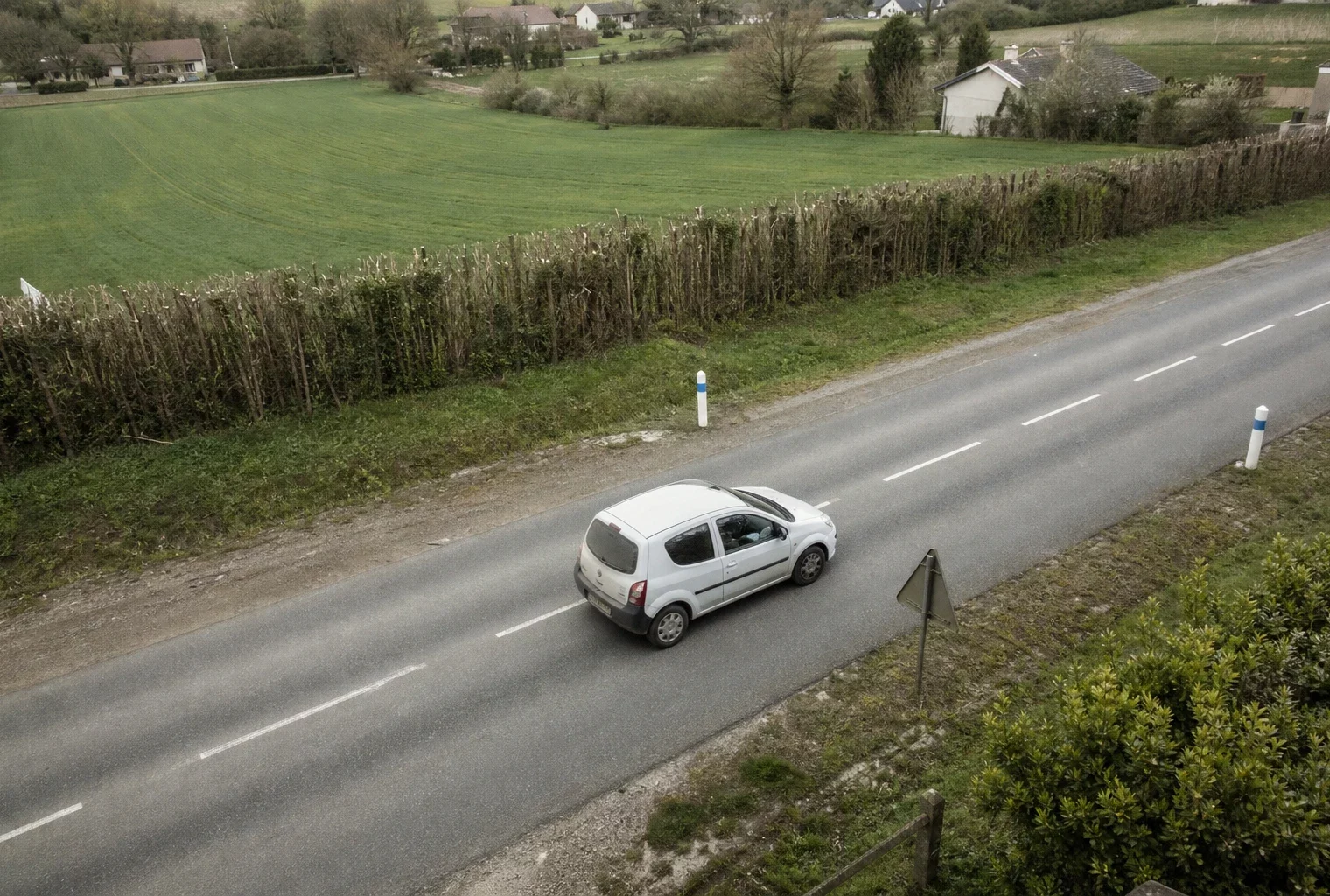 Une voiture roule sur une route de campagne, image du trajet domicile-travail dépendant de la voiture.