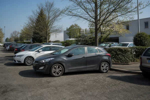 Voiture de trajet quotidien dans un parking ordinaire, pour illustrer les aides carburant destinées aux grands rouleurs.