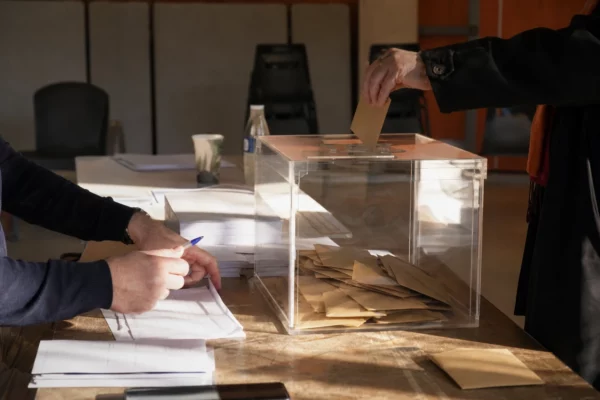 Table de vote interne avec bulletins, enveloppes et urne dans une salle de réunion des Écologistes.