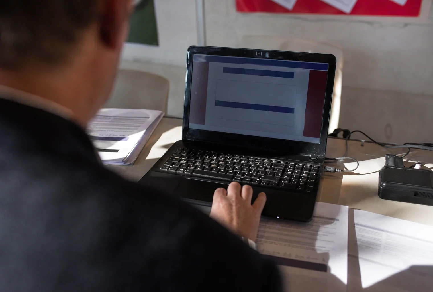 Un ordinateur prêt pour un vote en ligne dans un local de section socialiste, avec des feuilles de consignes à côté.