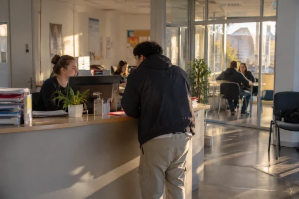 Comptoir et poste informatique dans un espace d’accompagnement vers l’emploi, avec des dossiers posés pour un rendez-vous.