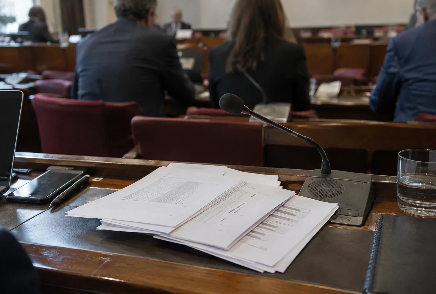 Pages d’un amendement budgétaire posées près d’un microphone, dans une salle de commission aux pupitres équipés.