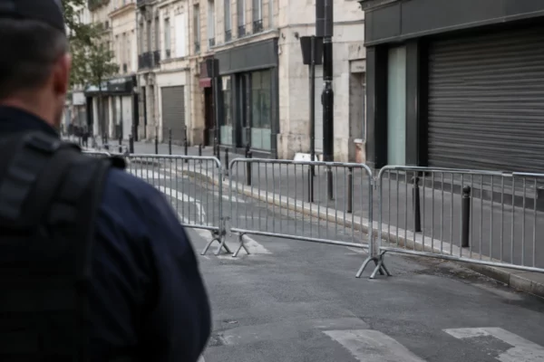Barrières mobiles alignées sur une rue urbaine, devant des façades et des commerces sans enseigne lisible.