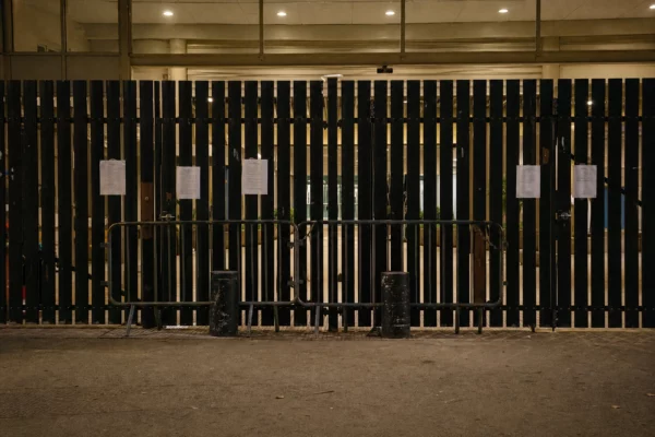 Grilles fermées d’un lycée français en fin de journée, avec barrières de blocage et façade scolaire en arrière-plan.