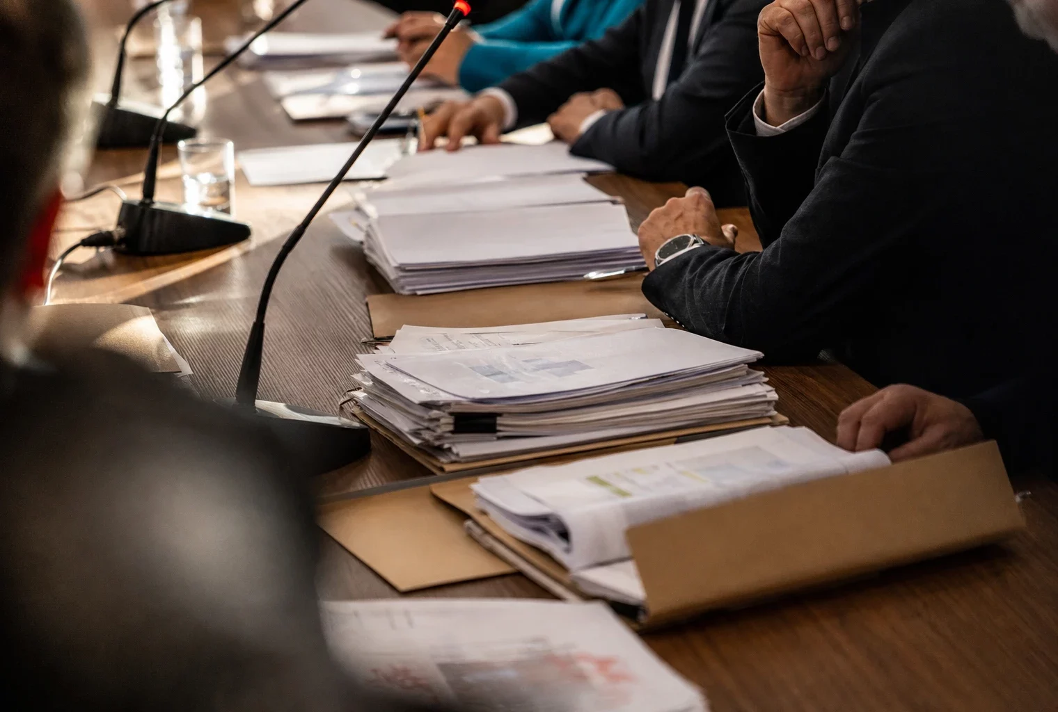 Dossiers budgétaires et chemises cartonnées sur une table de réunion, dans la salle sobre du Conseil des ministres.