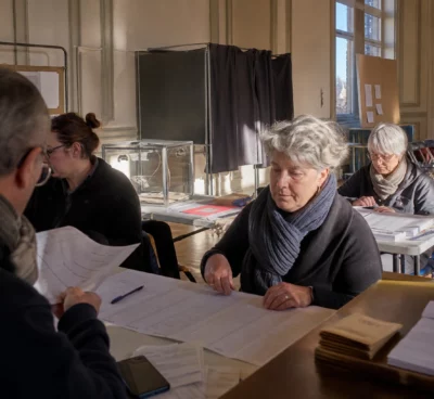 Un bureau de vote aménagé pour la primaire, avec tables d’émargement, isoloirs et bulletins sur place.