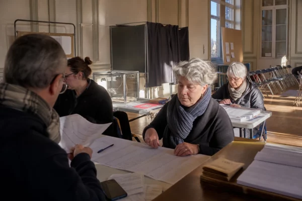 Un bureau de vote aménagé pour la primaire, avec tables d’émargement, isoloirs et bulletins sur place.
