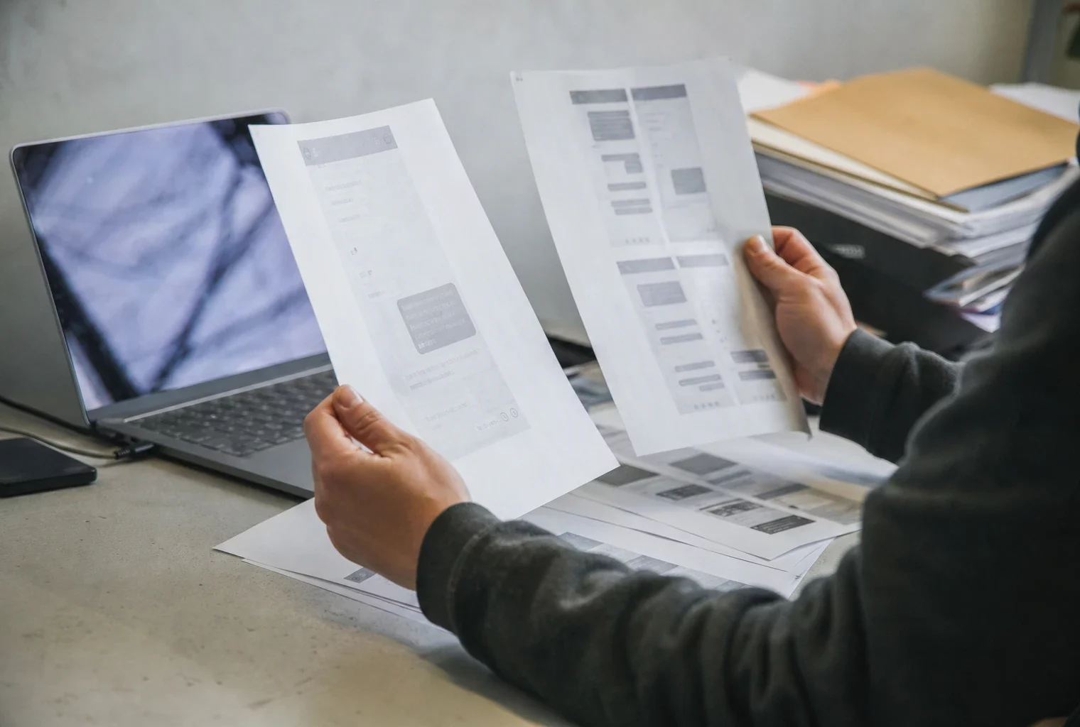 Des captures d’écran contestées et des documents imprimés posés sur une table de travail, avec un ordinateur ouvert à côté.