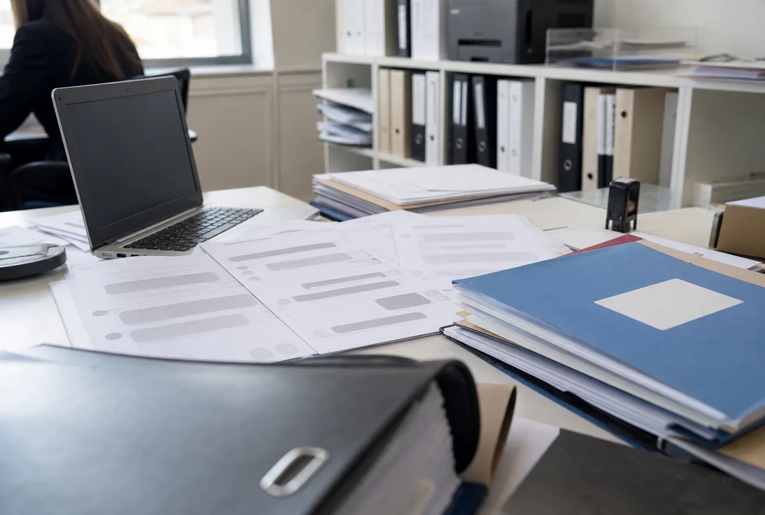Feuilles imprimées de conversations Messenger, ordinateur ouvert et dossiers de procédure dans un cabinet de commissaire de justice.