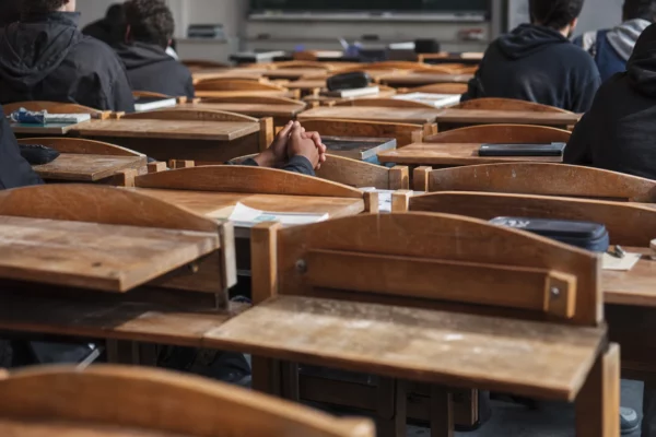 Salle de classe trop petite dans un lycée de Seine-Saint-Denis, rangées de chaises et tables serrées, quelques places vides.